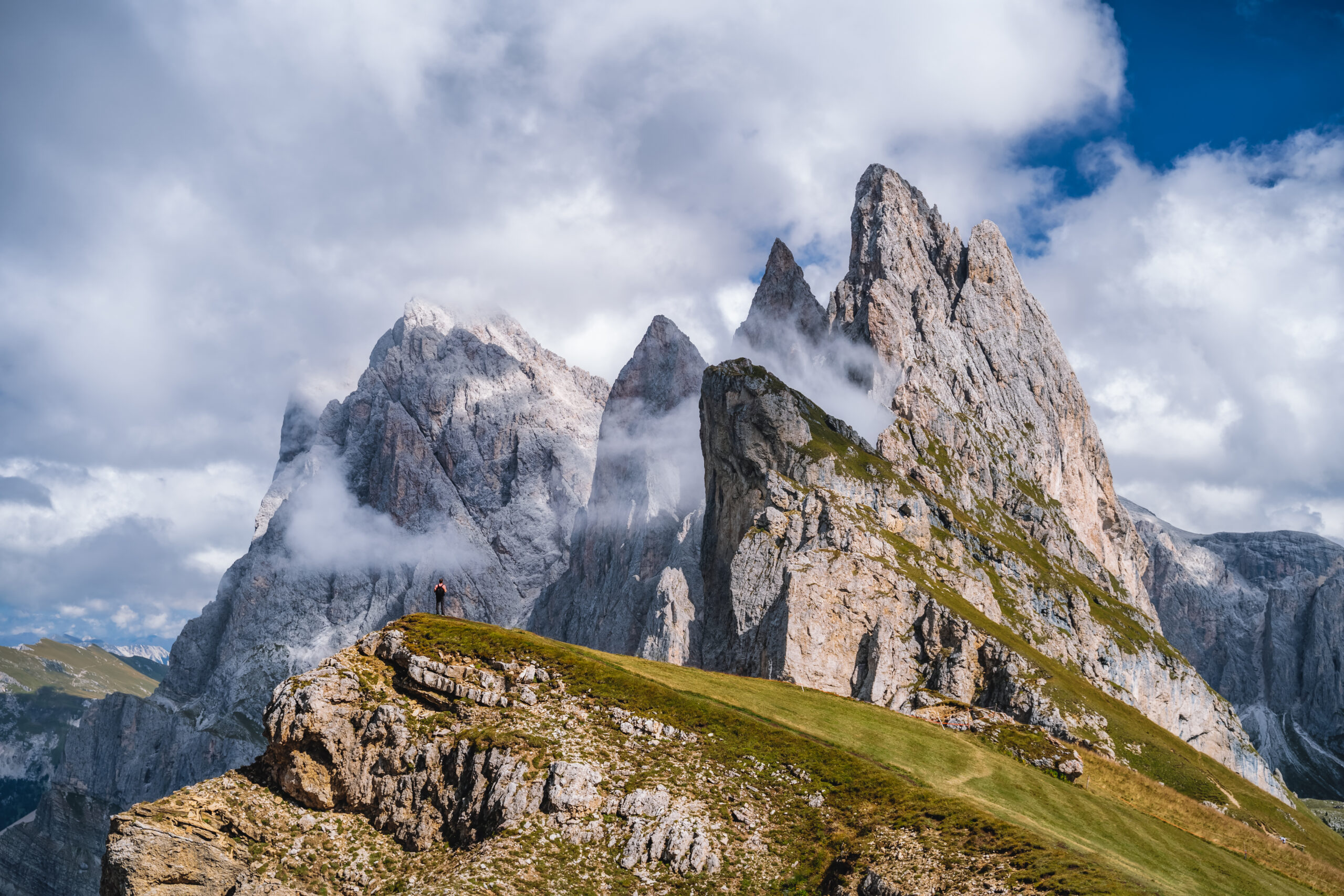 A man in front of epic Furchetta and Sass Rigais peaks in Seceda, Dolomites Alps, Odle mountain range, South Tyrol, Italy, Europe. Travel vacation concept.