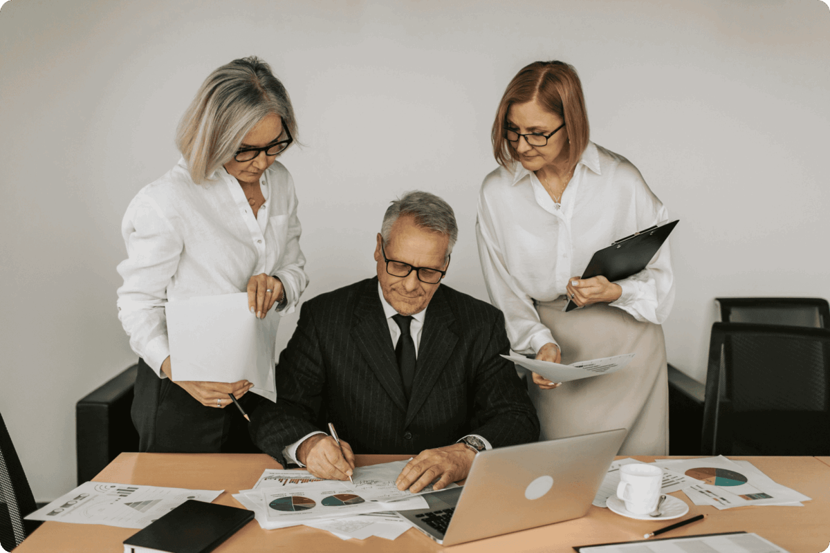 Business owner signing documents with OneAccord advisors reviewing financial statements and M&A strategy for selling business
